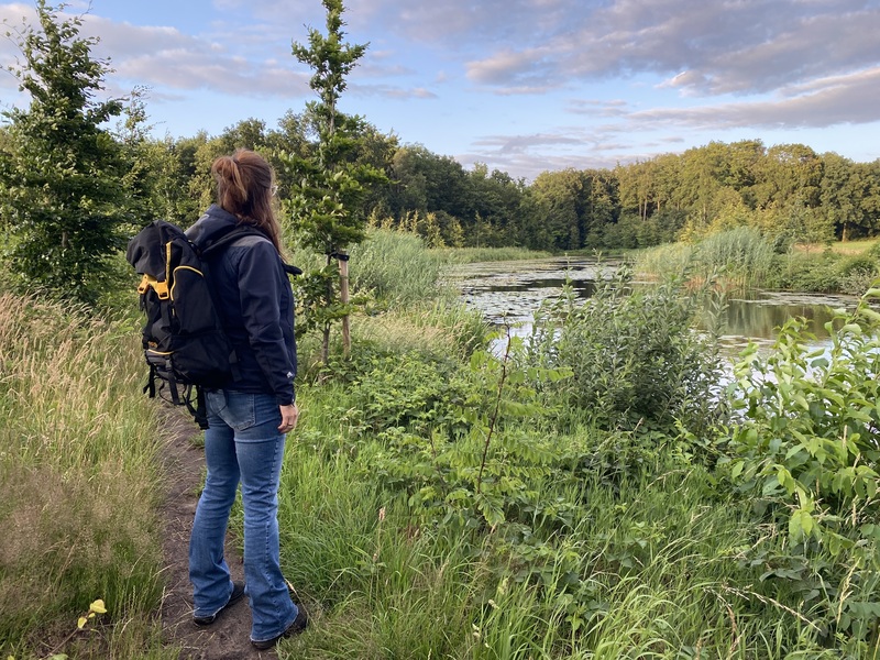 Wandelaarster met rugzak speurt door het Vechtdal tijdens een outdoor escape in Dalfsen—100% offline escaperoom buiten met kaart en kompas